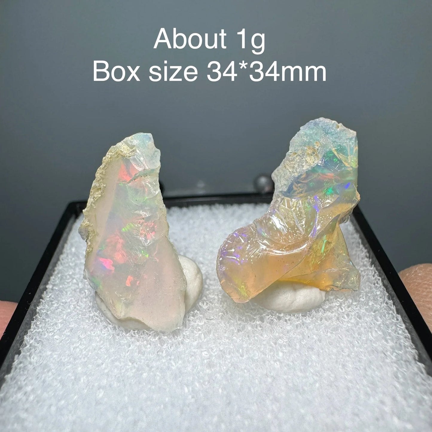 Two opal stones on a white cushion with text indicating weight and box size.