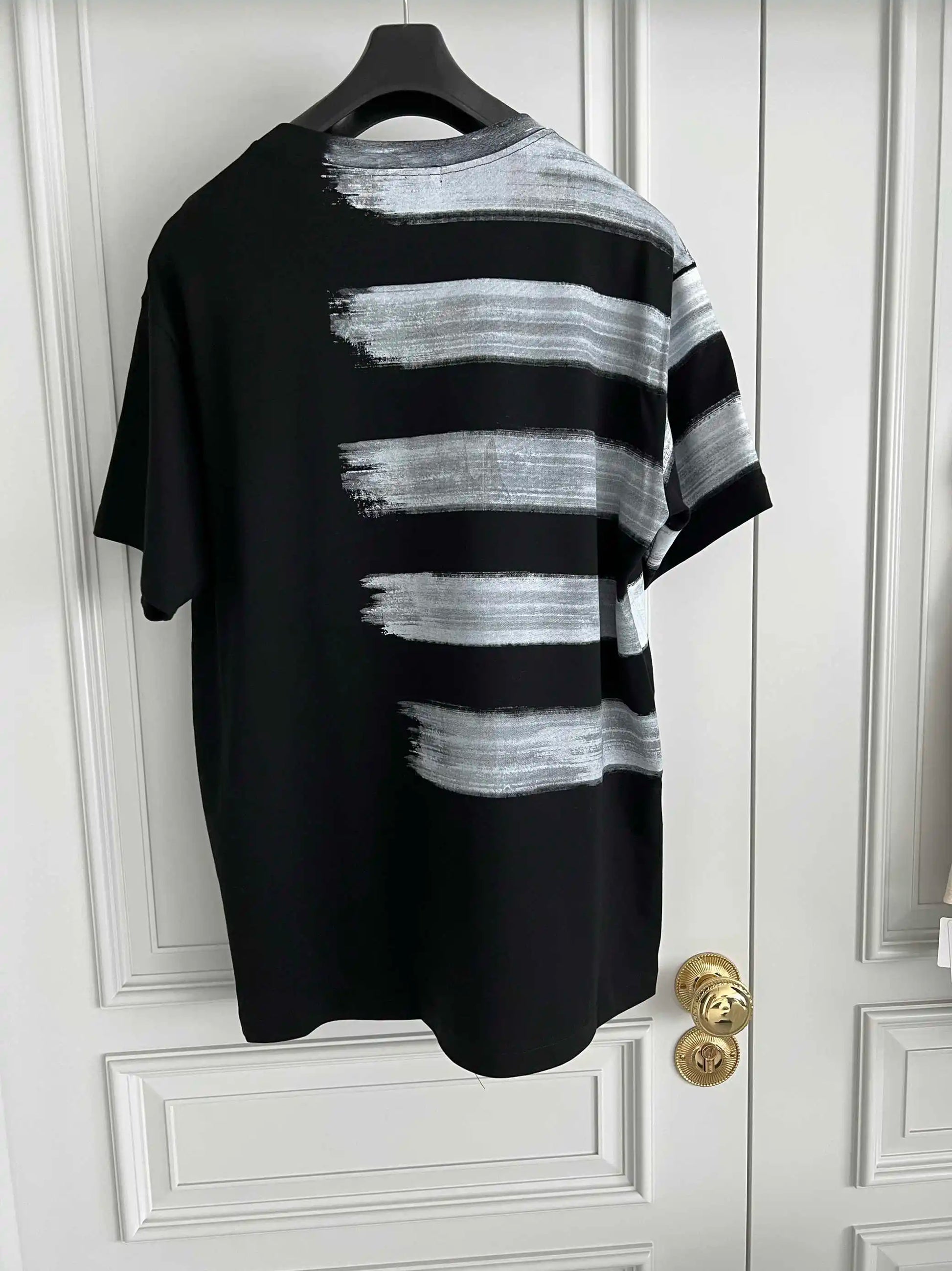 Black and white striped shirt on a hanger against a white door.