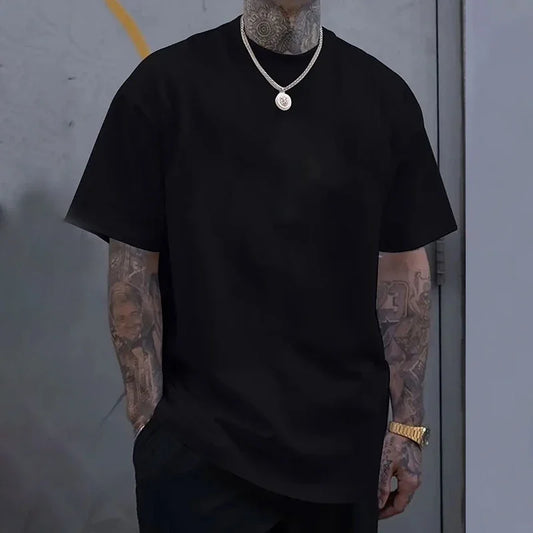 Person wearing a black t-shirt with tattoos on arms against a gray background