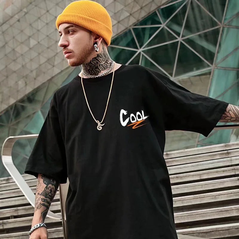 Person wearing a black t-shirt with 'COOL' printed on it, standing outdoors.