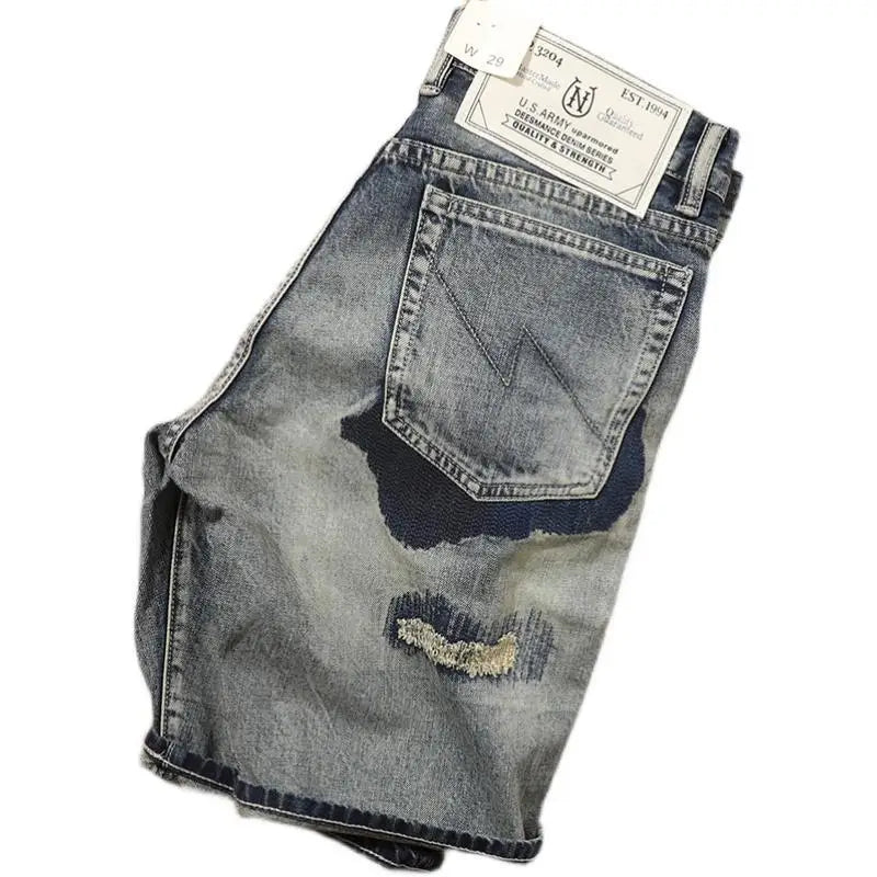 Stacked pair of distressed denim jeans with a brand label on a white background