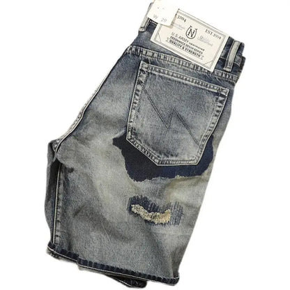 Stacked pair of distressed denim jeans with a brand label on a white background