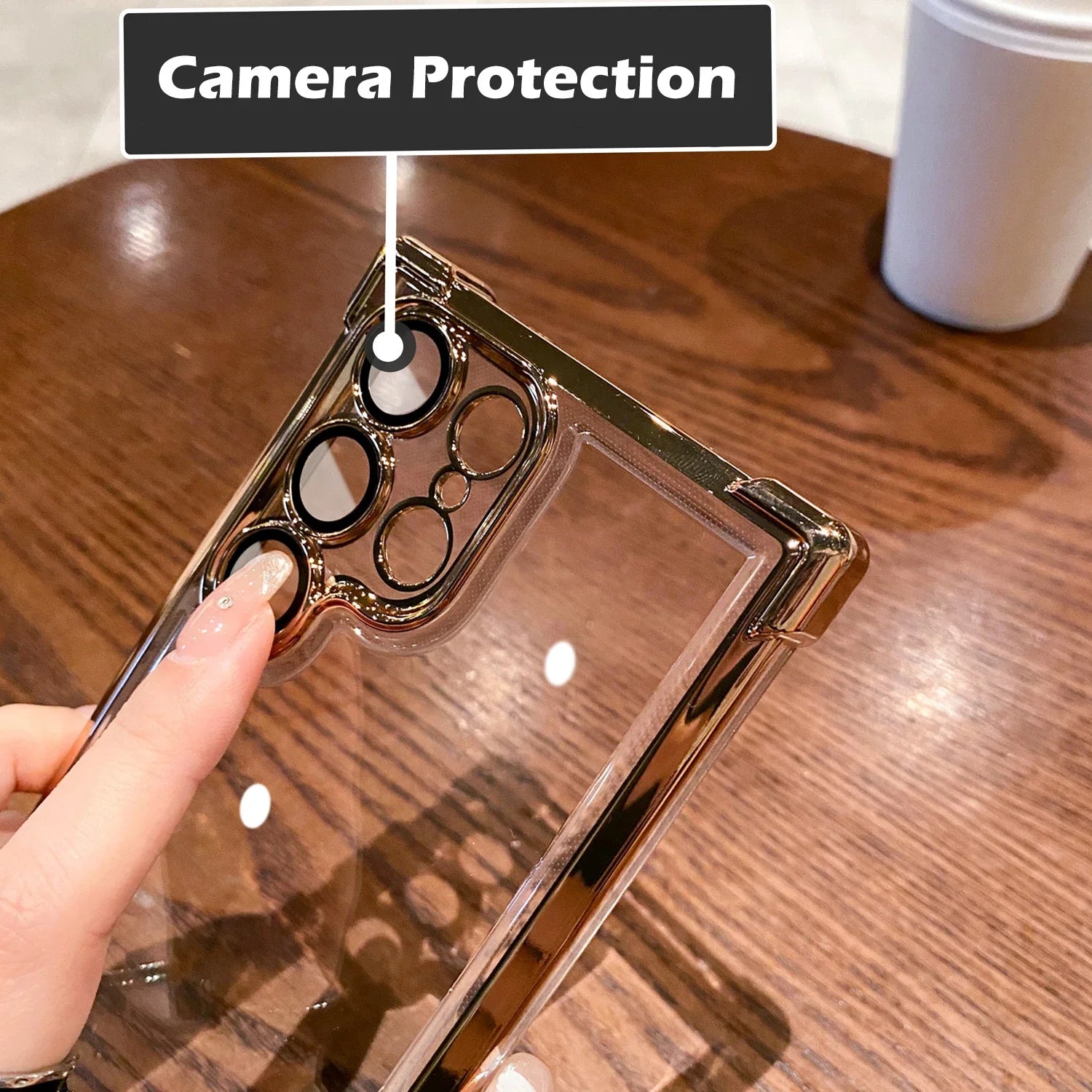 Phone case with camera protection feature held by a hand on a wooden surface.
