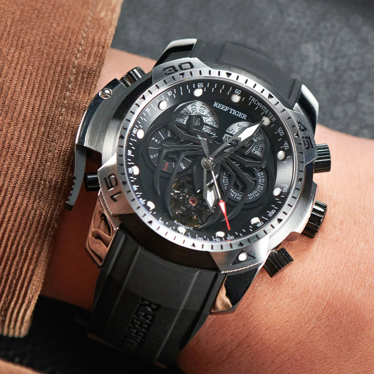 Reef Tiger watch on a person's wrist with a brown jacket sleeve.