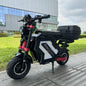 Electric scooter with a black and red design parked on a sidewalk in an urban setting.