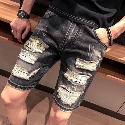Ripped black denim shorts worn by a person on a wooden floor.