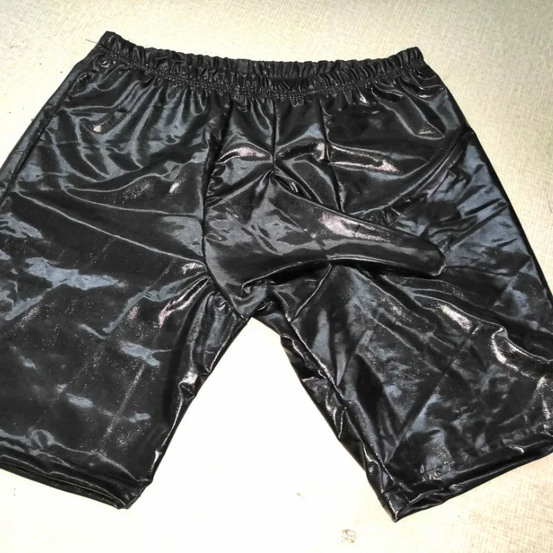 Black shiny shorts on a textured beige surface