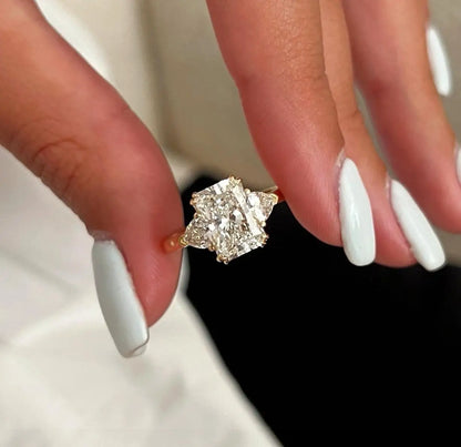 Diamond ring on a hand with white nail polish against a neutral background
