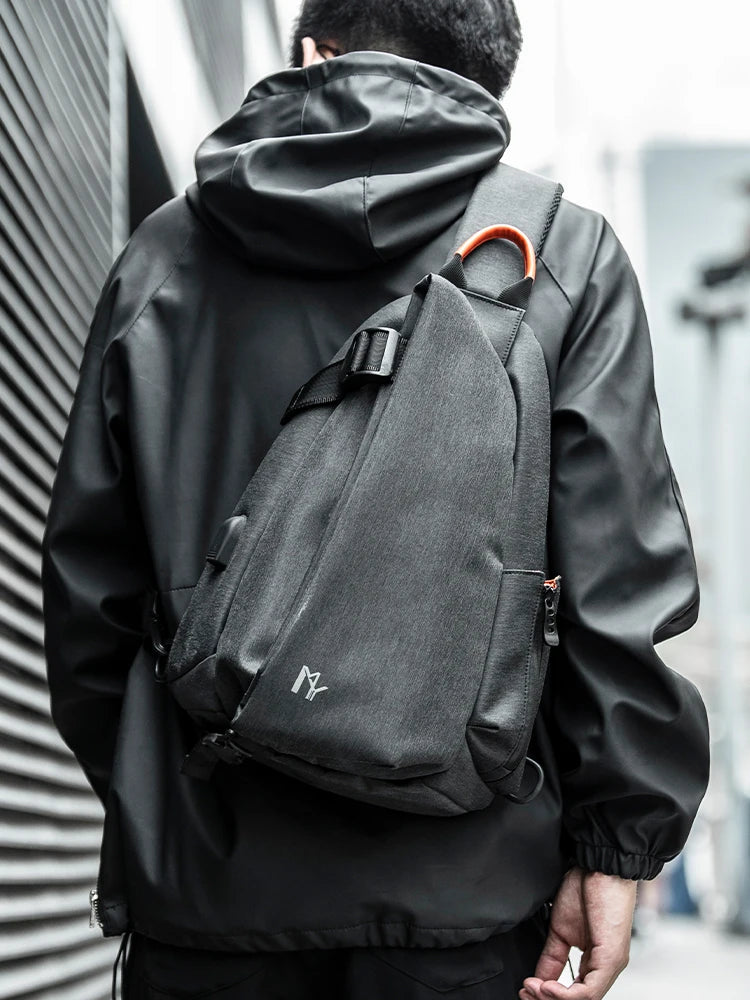 Person wearing a black raincoat with a gray backpack in an urban setting