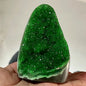 Green crystal held in a hand against a neutral background
