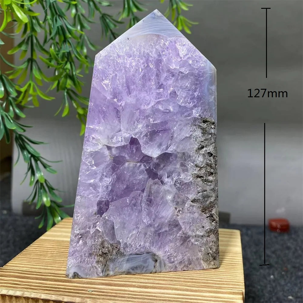 Purple crystal tower on a wooden stand with a plant in the background