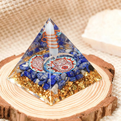 Pyramid-shaped decorative item with blue stones and a white candle on a wooden base