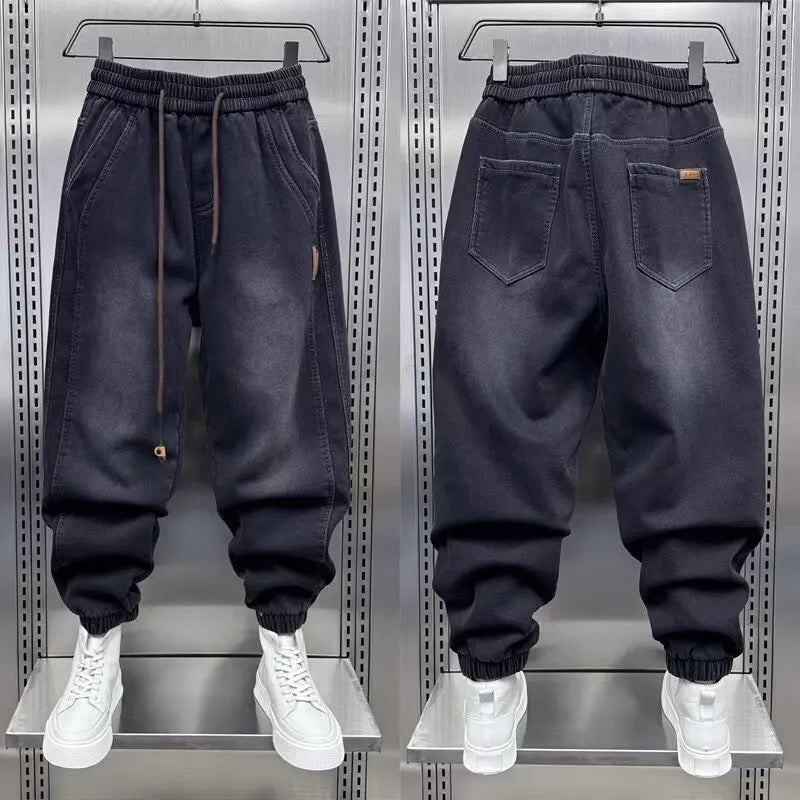 Black jogger pants displayed on a metallic rack with white sneakers.