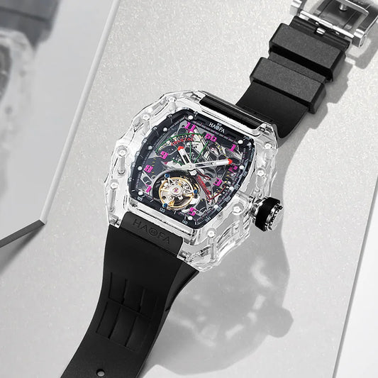 A luxury watch by HAGFA, featuring a transparent crystal case, a black rubber strap, and a skeletonized dial with a visible tourbillon and pink accents.