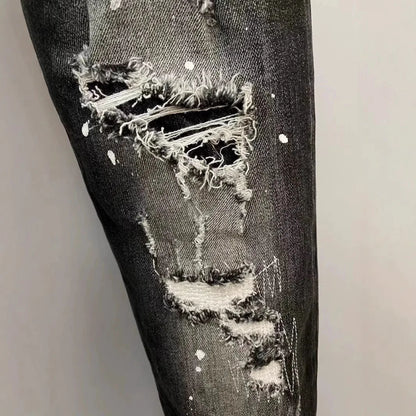 Distressed black denim jeans with a large hole in the knee area on a light gray background.