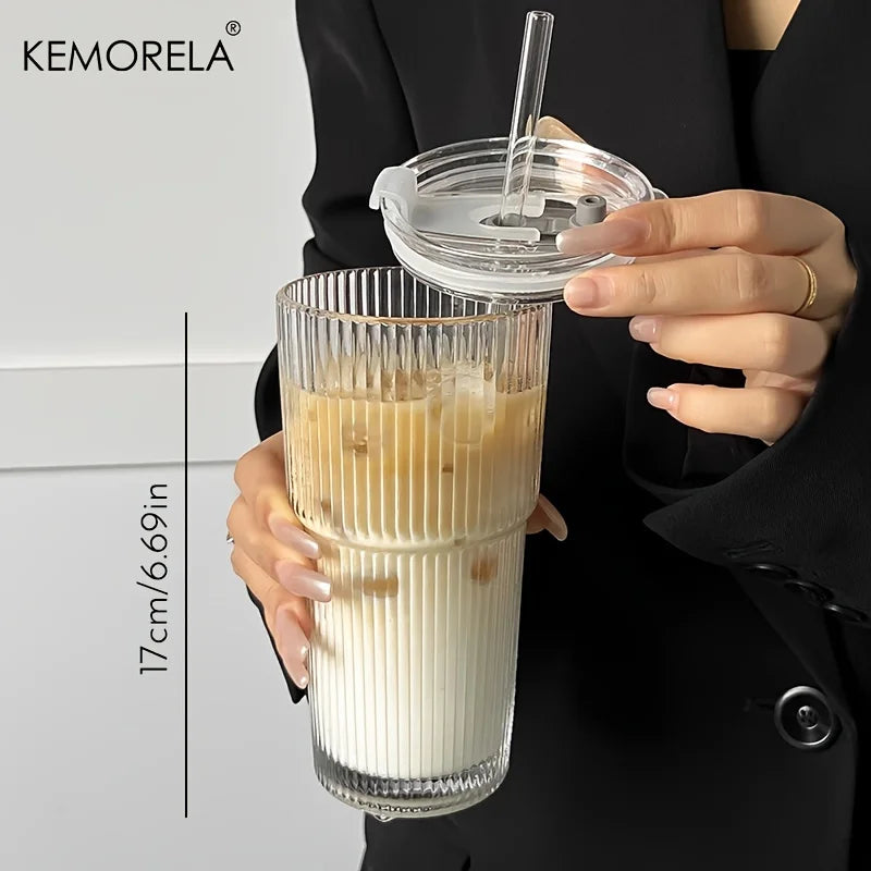 Clear glass with a straw and lid held by a person, with KEMORELA branding.