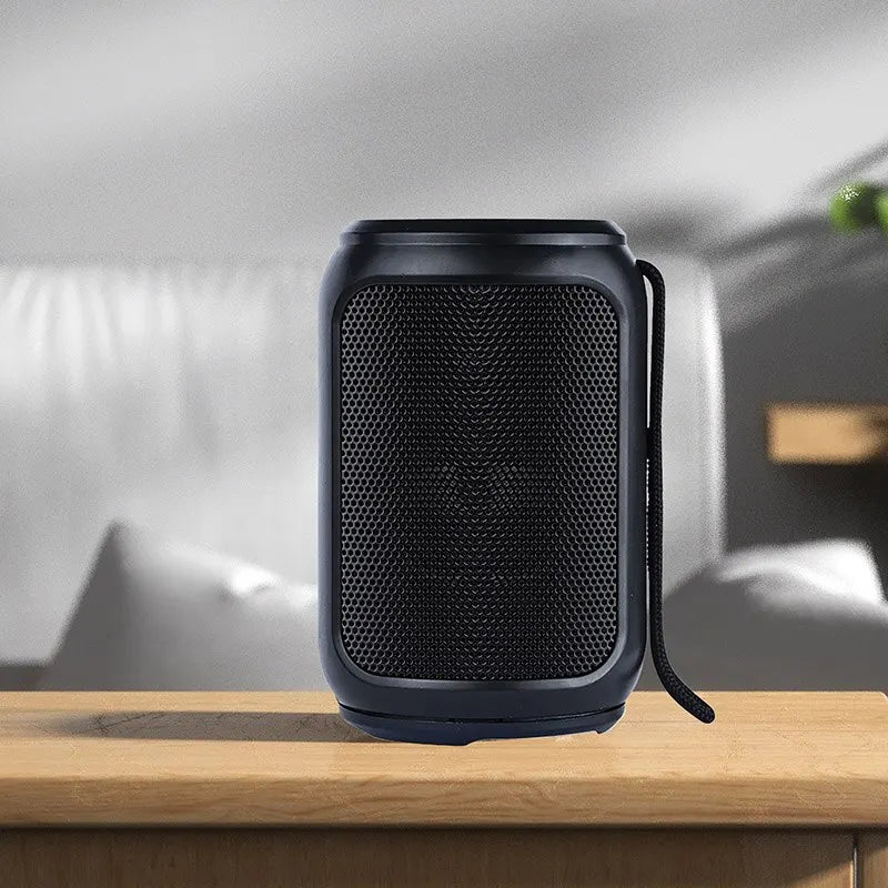 Black portable speaker on a wooden surface with a neutral background