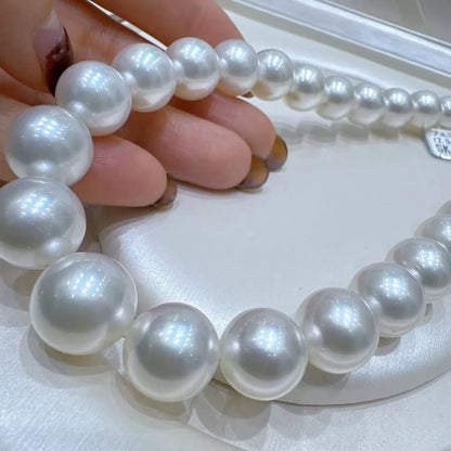 Pearl necklace held by a hand on a white surface