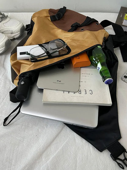 Open backpack with items including a laptop, books, and a bottle on a white surface.