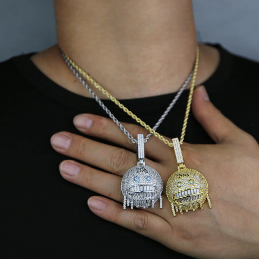 Two robot-shaped pendants on chains held by a person against a dark background