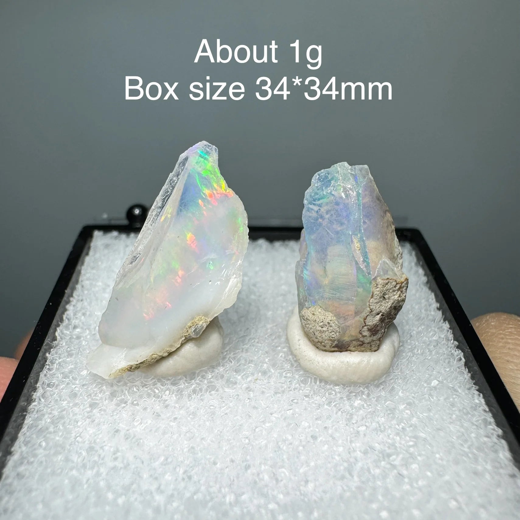 Two opal stones on a black stand with text about weight and box size.