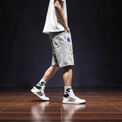 Person wearing white sneakers with black stripes, light gray shorts, and black socks with a logo on a dark background.