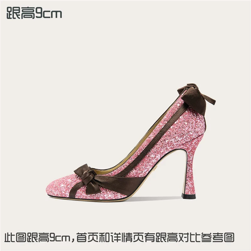 Pink glitter high heel shoe with brown accents on a white background