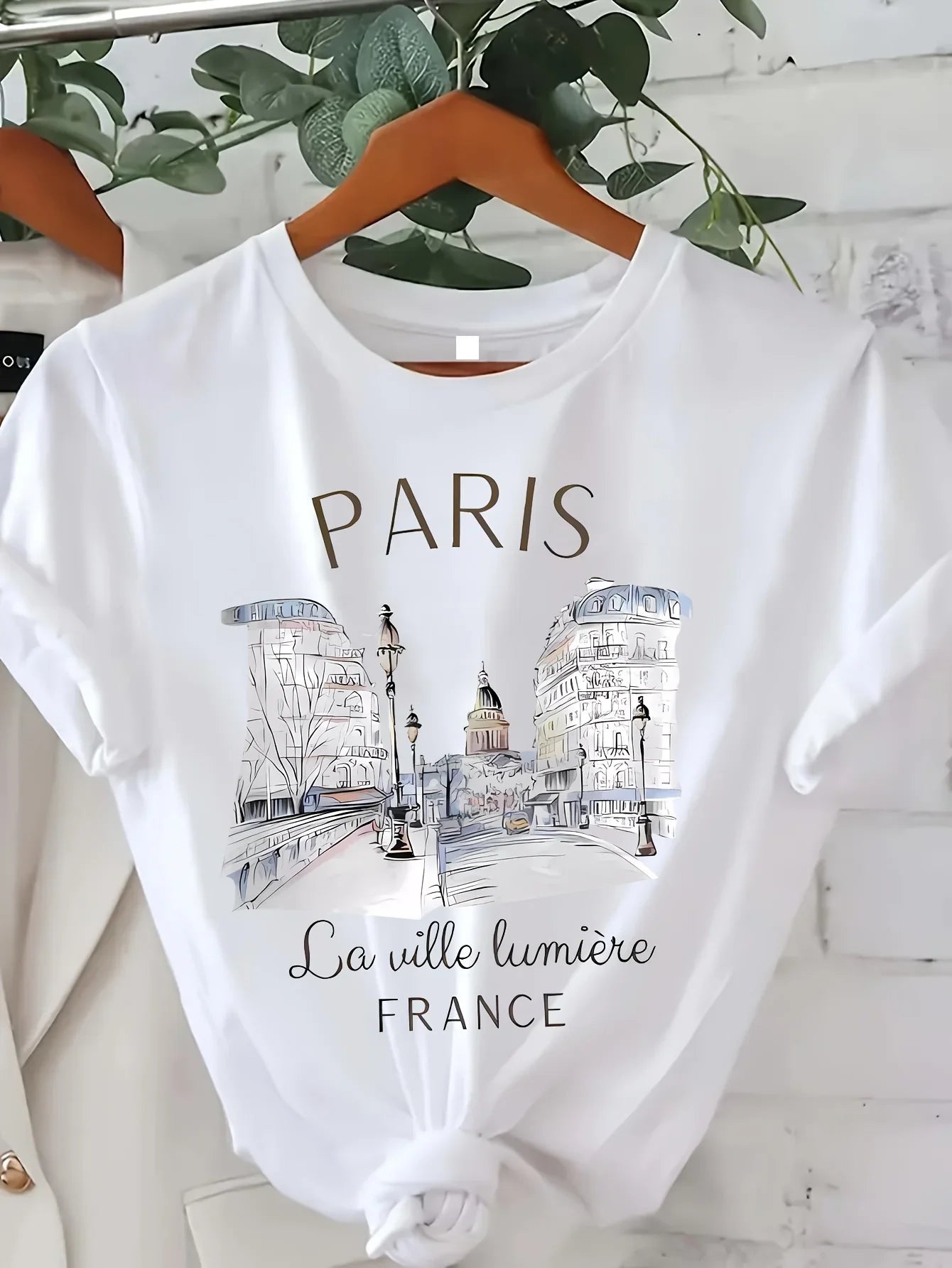 White t-shirt with Paris-themed design on a hanger