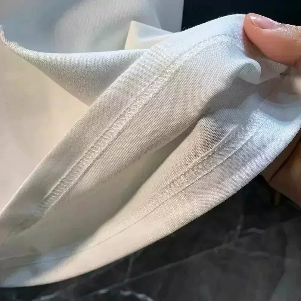 Close-up of a white fabric with visible stitching held by a hand.