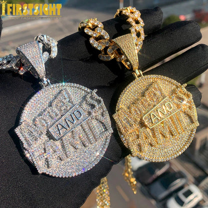 Two gold and silver pendants with 'AND' text on a black surface.