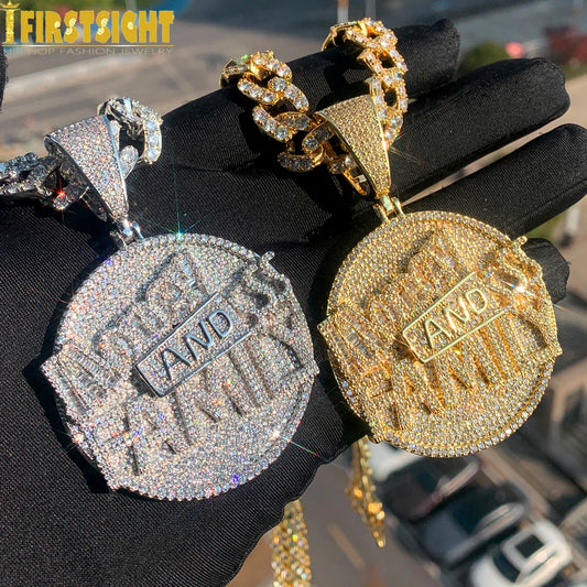 Two gold and silver pendants with 'AND' text on a black surface.