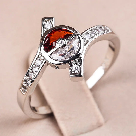 Silver ring with a red gemstone and clear stones on a beige background