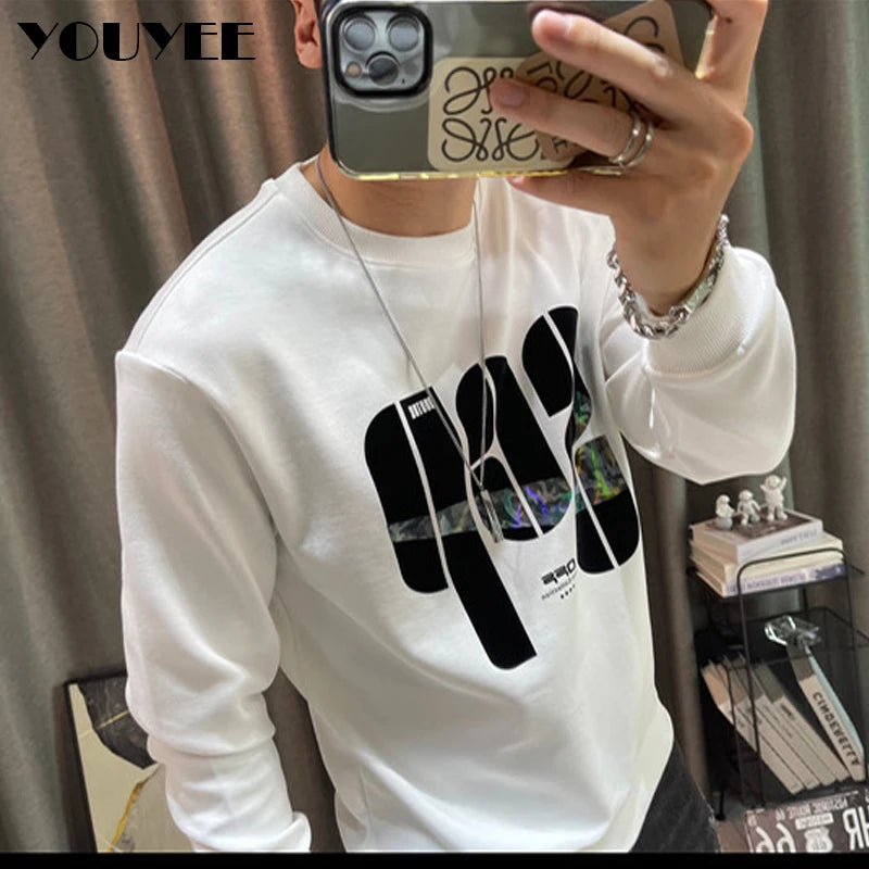 Person wearing a white sweatshirt with black graphics, holding a phone with a reflective case.