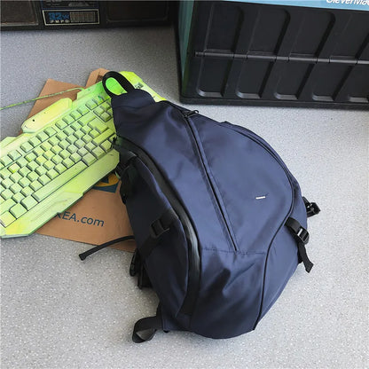 Blue backpack on a gray floor with a green keyboard and cardboard box in the background.