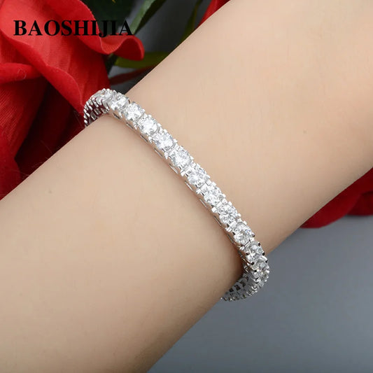 Silver bracelet on a wrist with a blurred red flower in the background, featuring the brand 'BAOSHILIA'.