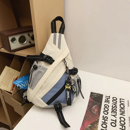 White and blue sling bag with black accents on a white surface with a magazine underneath.