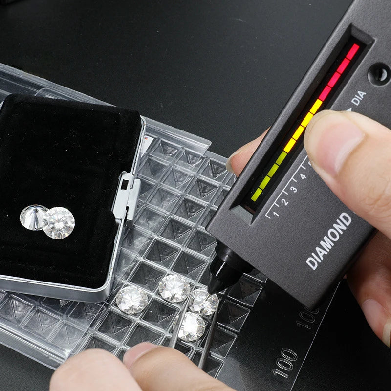 Diamond quality tester being used on a diamond next to a jewelry box.