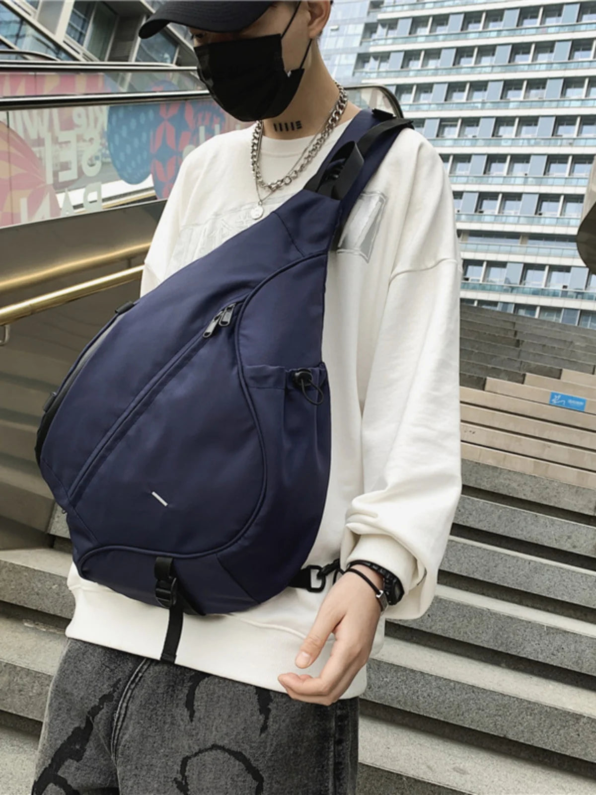 Person wearing a navy blue sling bag in an urban setting