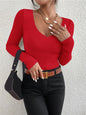 Person wearing a red sweater and black pants with a neutral background