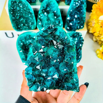 Teal crystal rock held by a hand with a blurred background