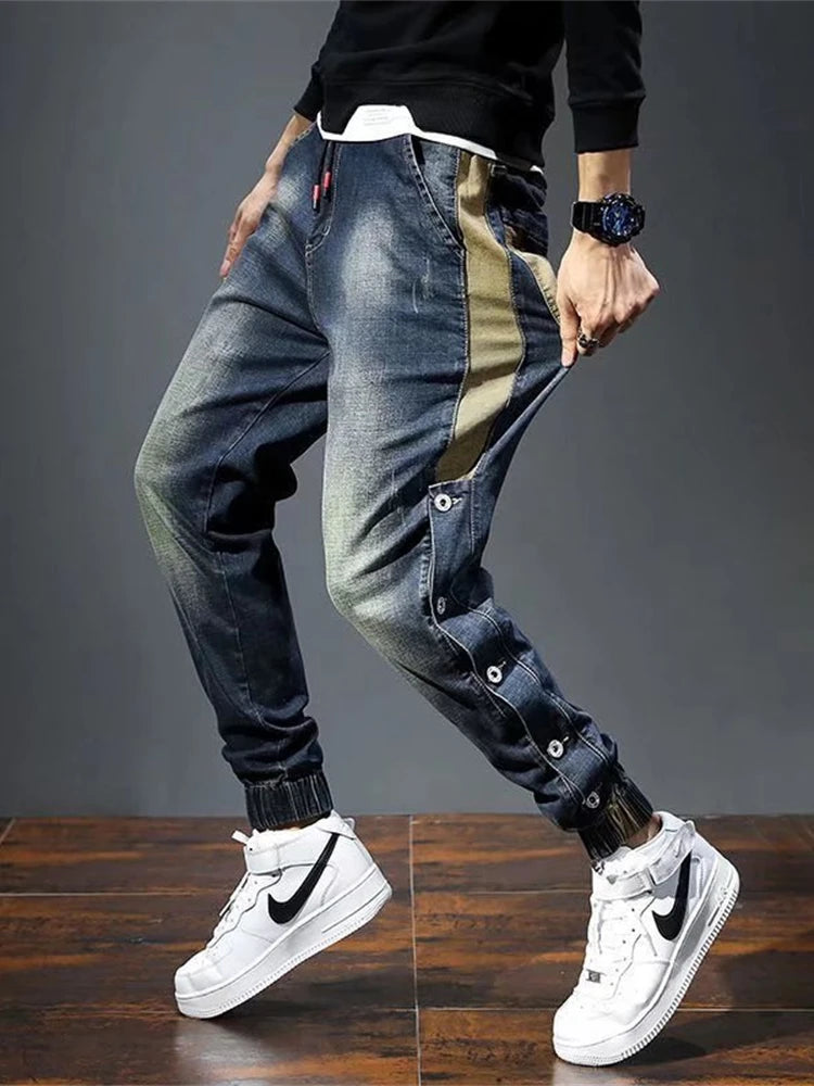 Person wearing blue jeans and white sneakers on a wooden floor with a gray background