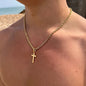 Gold necklace with a cross pendant on a person against a beach background