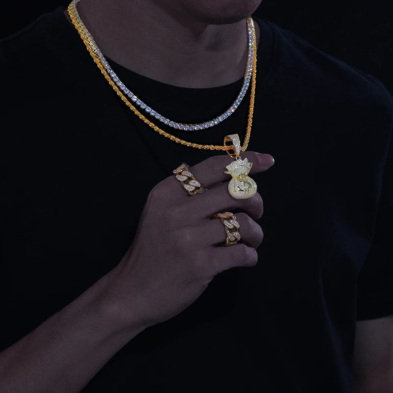 Gold jewelry including necklaces and rings held by a person against a black background