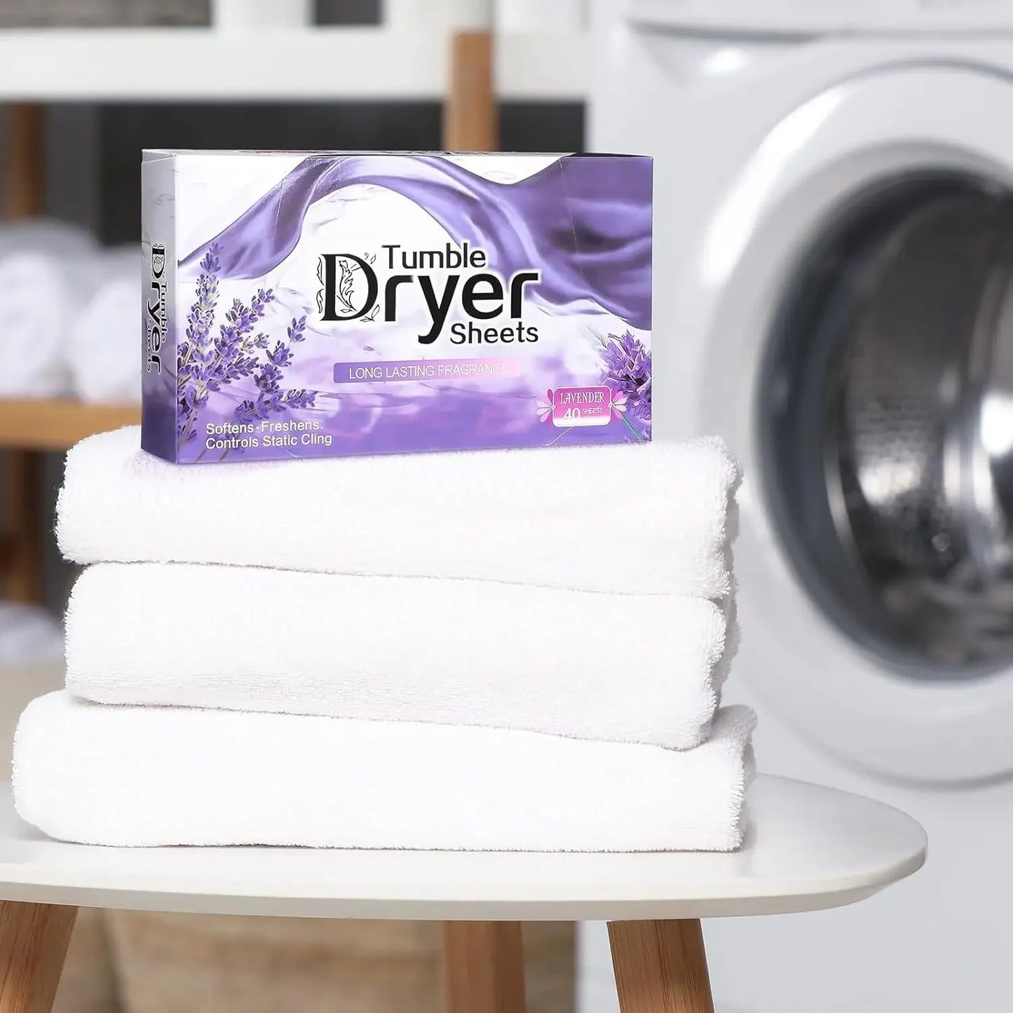 Stack of white towels with a box of Tumble Dryer Sheets in front of a washing machine.