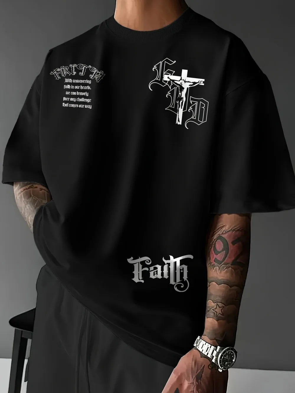 Black t-shirt with white graphics and text worn by a person against a gray background