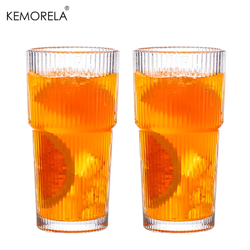 Two glasses of orange juice with a white background and 'KEMORELA' branding.