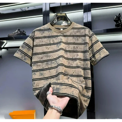 Striped t-shirt on a hanger with a hand holding it, against a blurred indoor background.