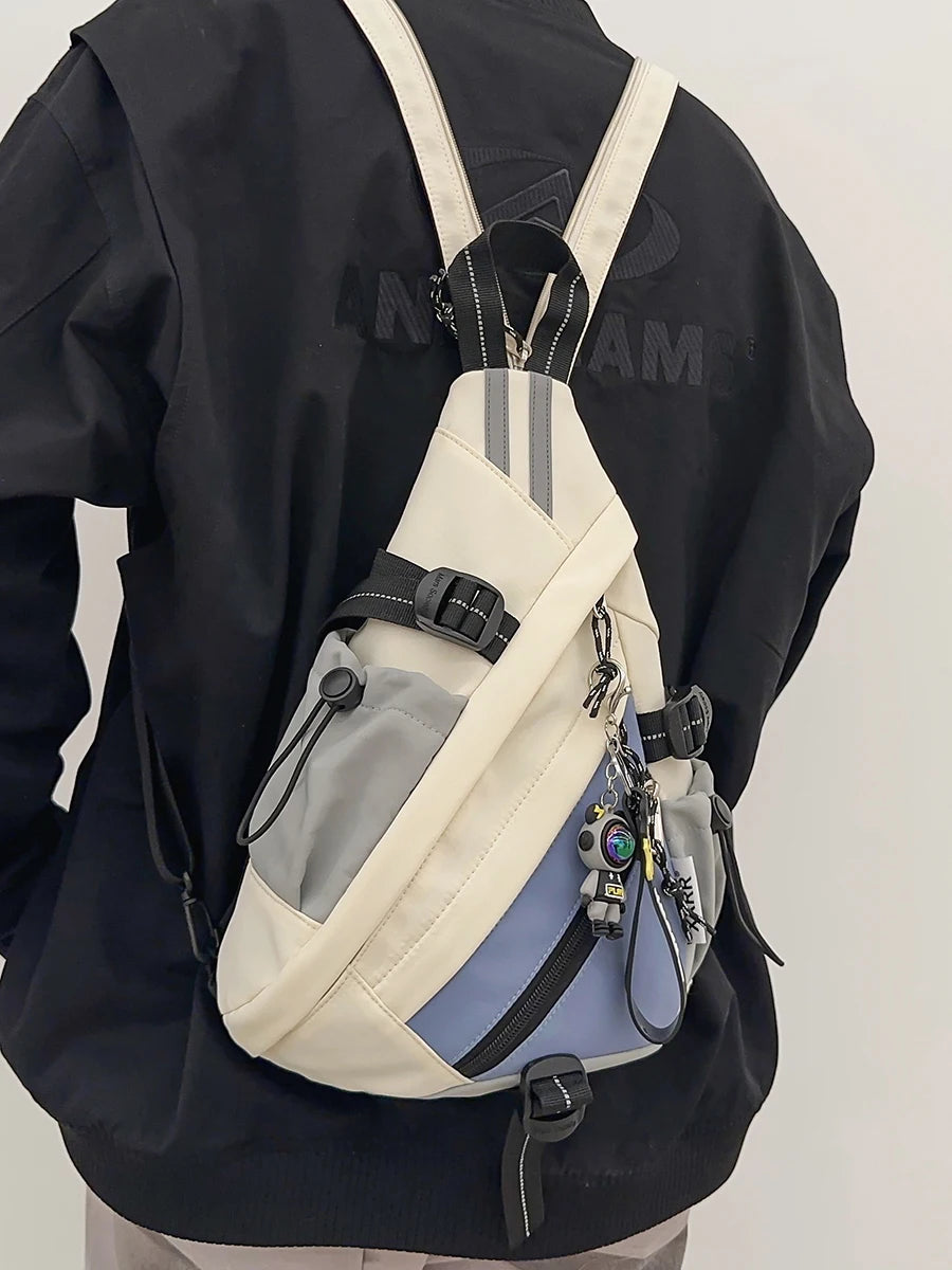 Person wearing a black jacket with a beige and gray sling bag on a white background