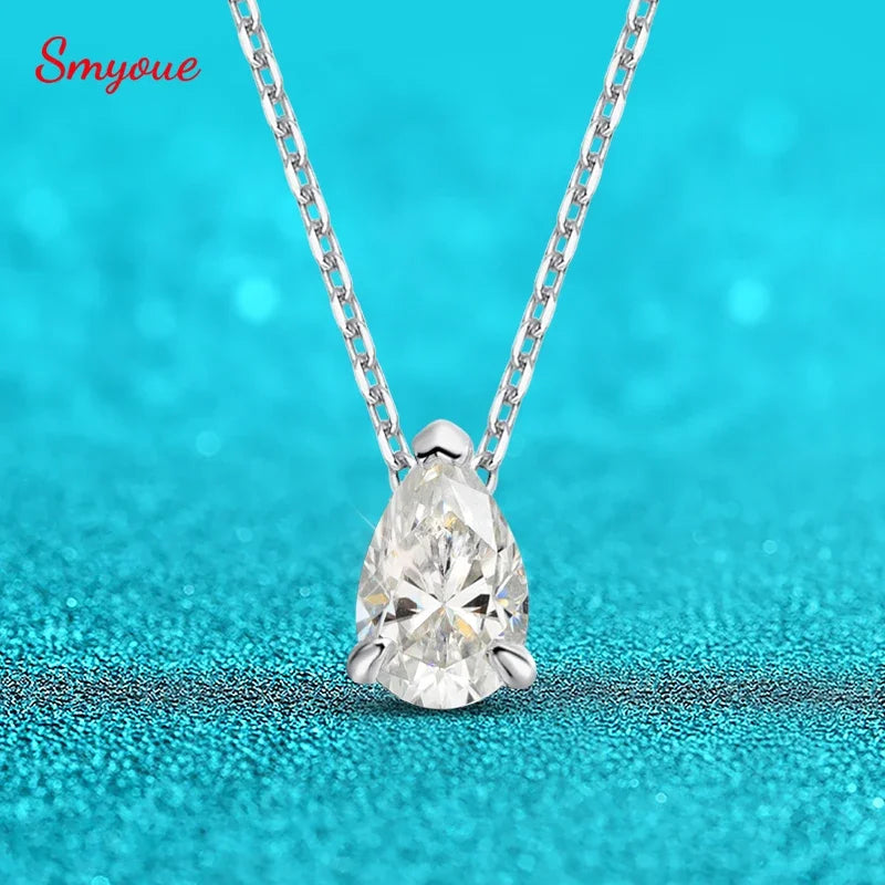 Teardrop-shaped diamond pendant on a chain against a turquoise background