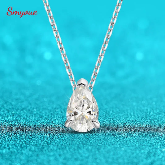 Teardrop-shaped diamond pendant on a chain against a turquoise background